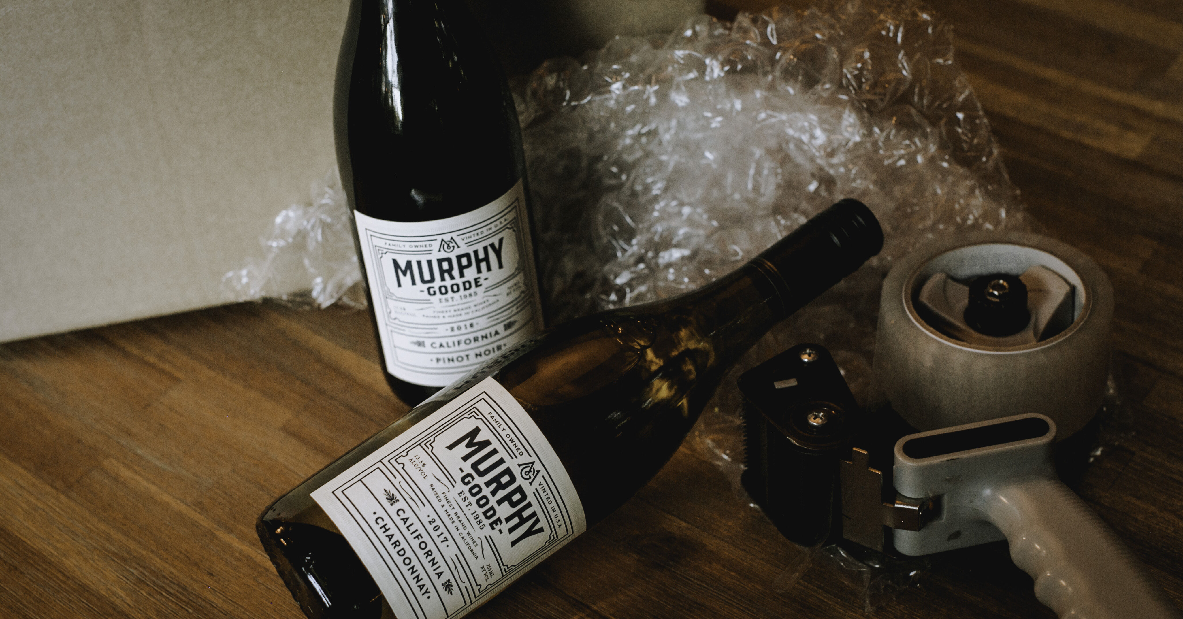 Murphy-Goode wine bottles on a table with bubble wrap and packaging tape